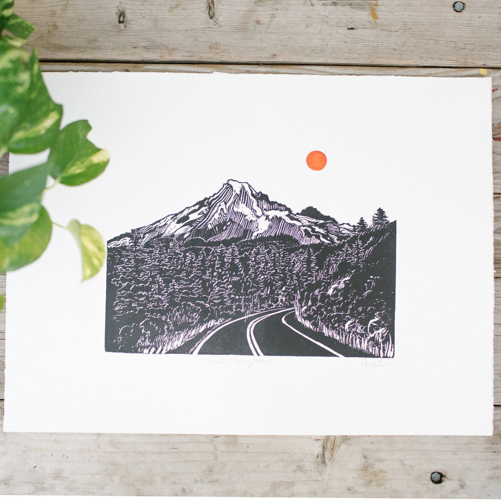 hand carved and pressed black and white 5x7 print of a road through the mountains and trees with a red sun 