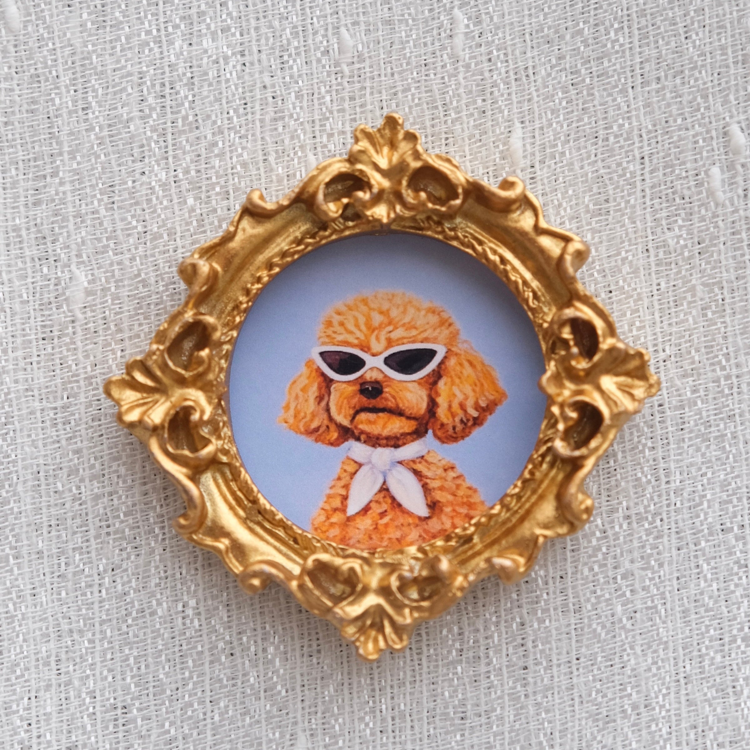 A poodle wearing cat eye sunglasses with an ascot tied around her neck. 