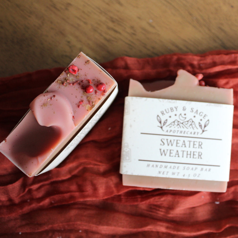Warm brown and pink soap with small red berries sprinkled on top. Pictured against a rust colored table runner.