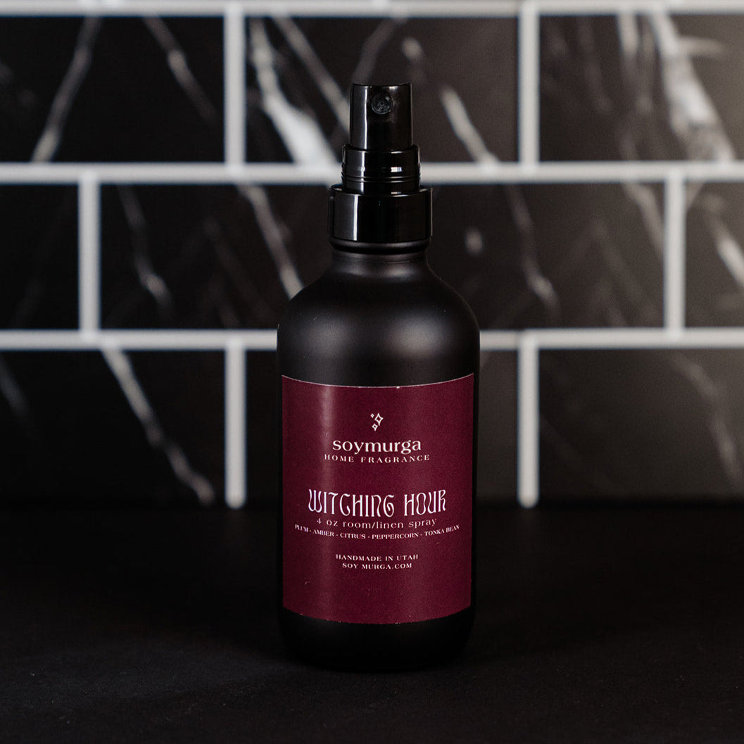 Black matte bottle with a burgundy label. Pictured against a black marble back splash. 