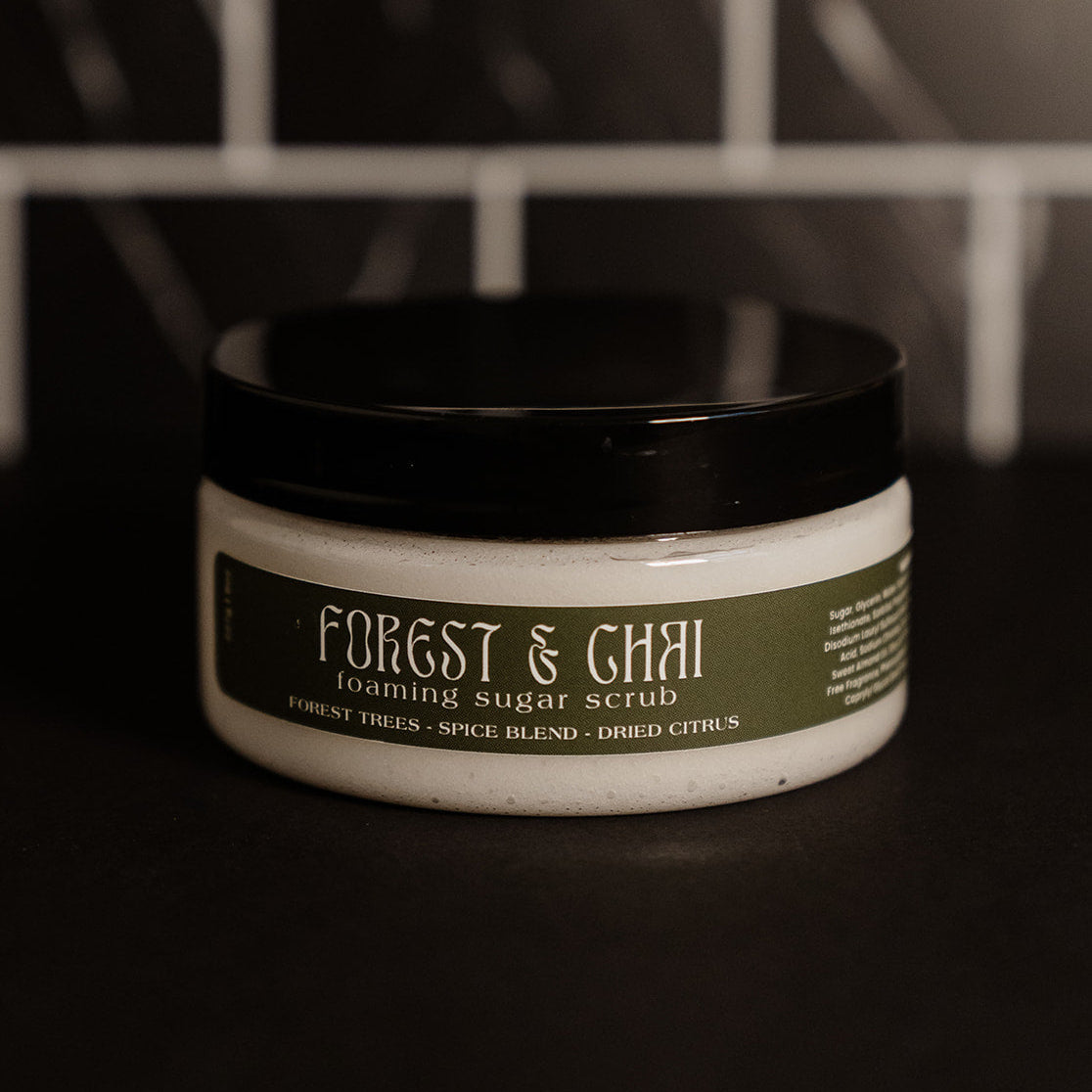 Small clear container with a black lid and a moss green label. Pictured against a black marble back splash. 