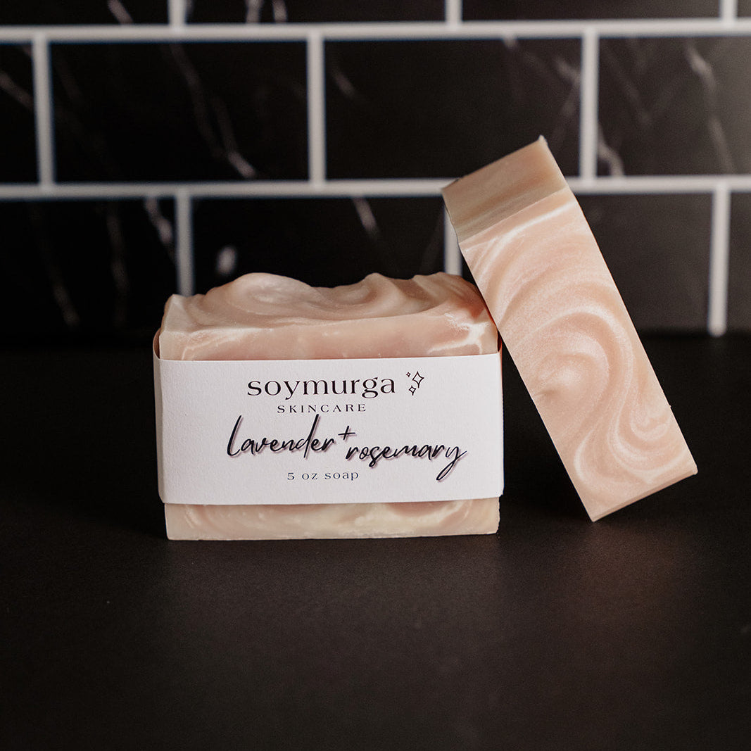 Lavender + rosemary soap bar on a black countertop with black marble subway tile in the background. 