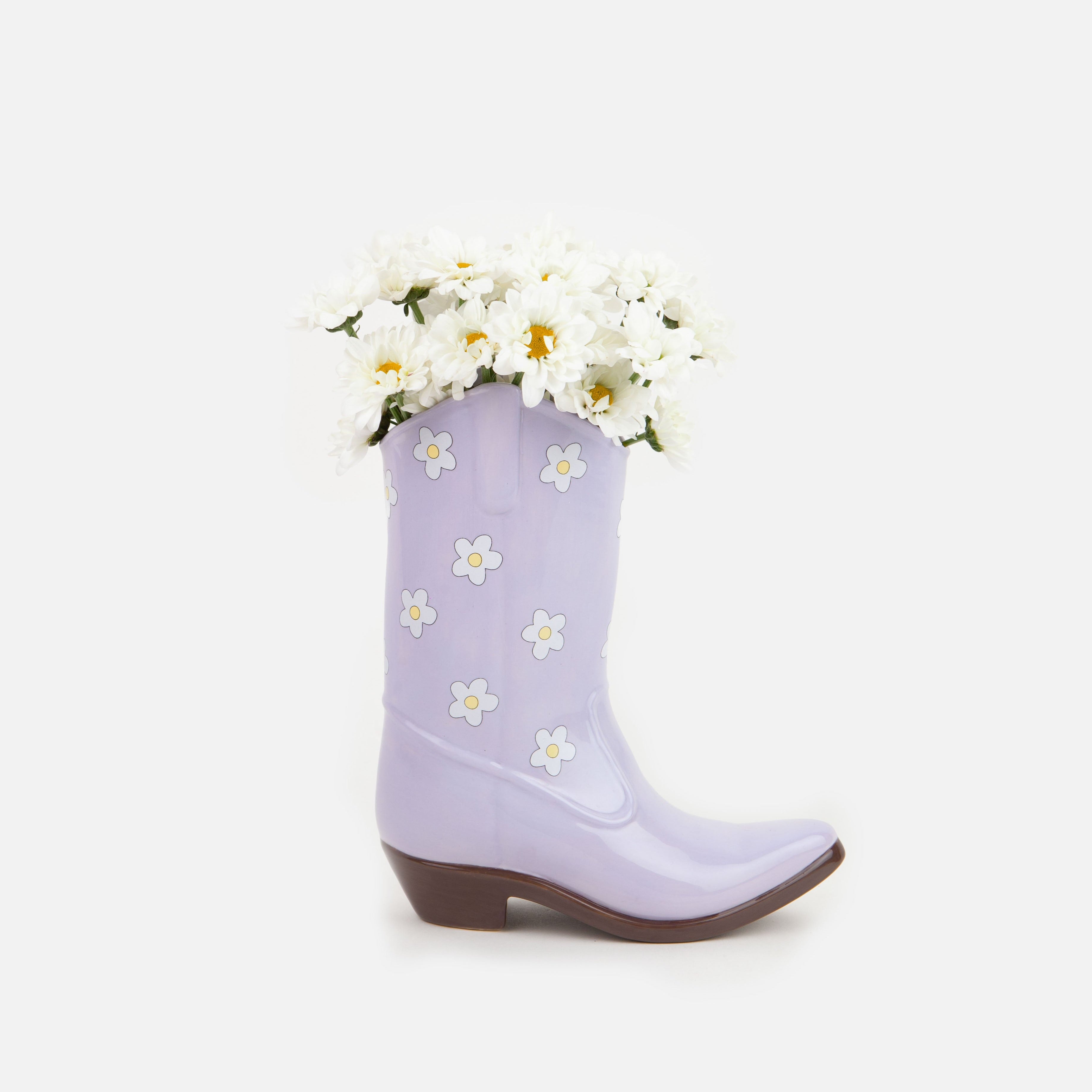 Saddle up and add a touch of whimsy to your home decor with our Lilac Cowboy Boot Vase. This unique boot-shaped vase in a lovely lilac color will add a playful touch to any room, while also providing a stylish way to display your favorite flowers. Giddy up and grab one today!