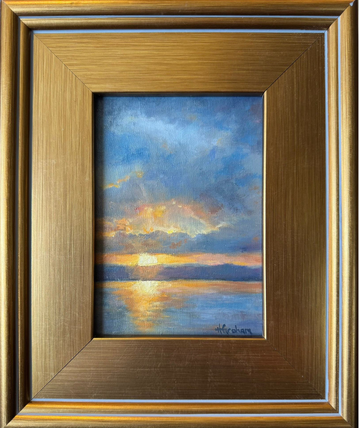 Framed painting of a sunset over water with a gold frame