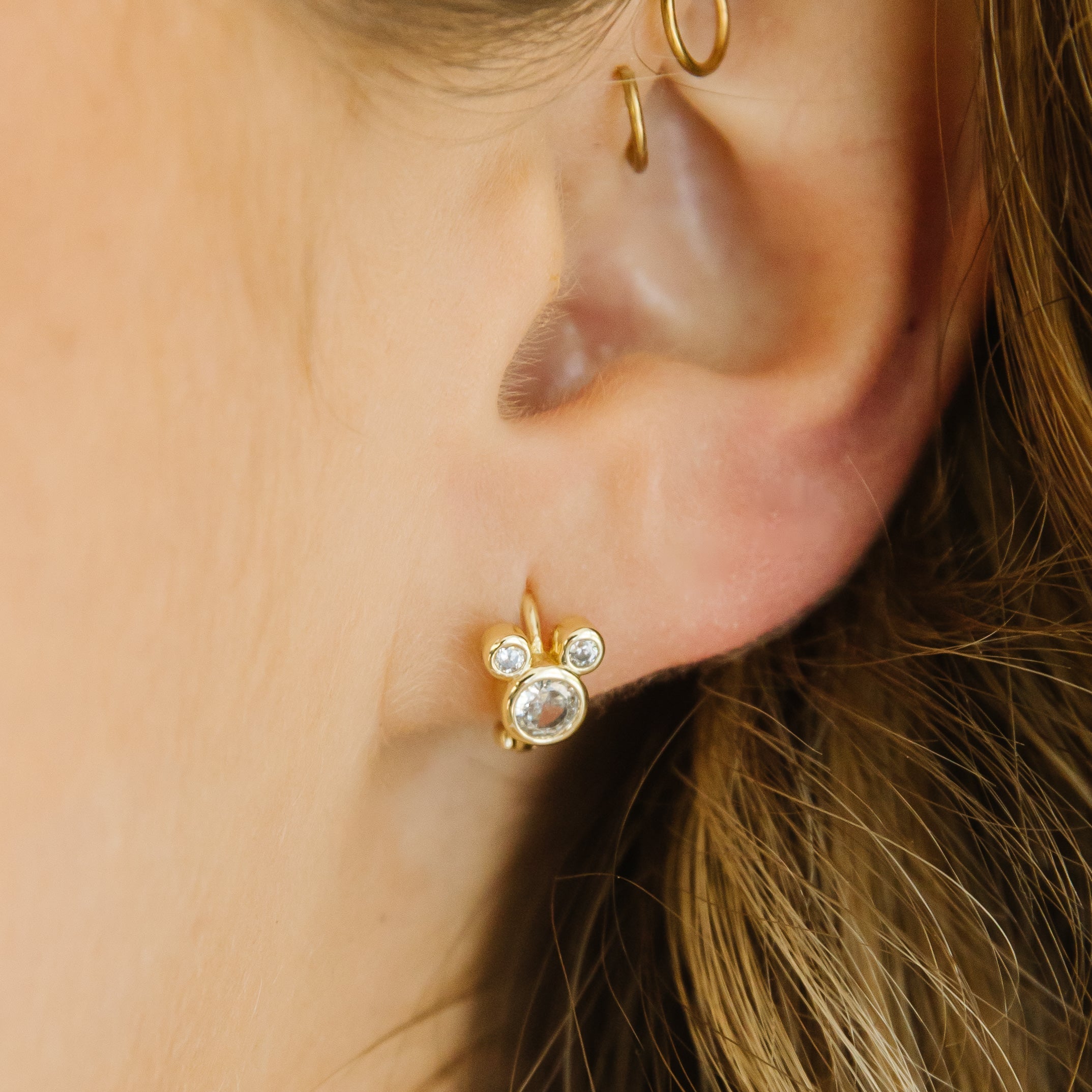 A model wearing the mickey mouse huggie showing it in her ear. 