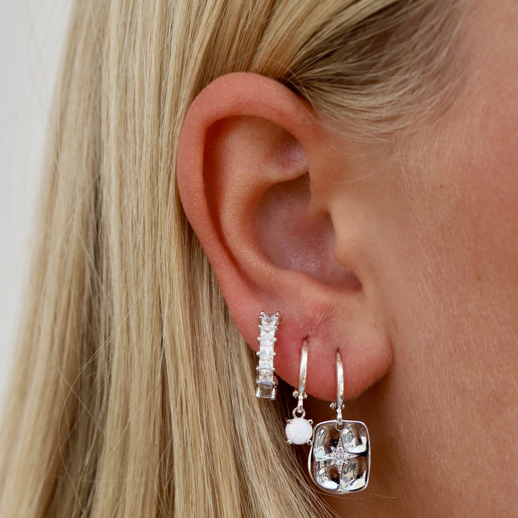 We can't get enough of our pressed styles! This silver huggies features a misshapen rectangular north star that drops down from the huggie, creating an effortless, lightweight style that you'll want to style 24/7.
