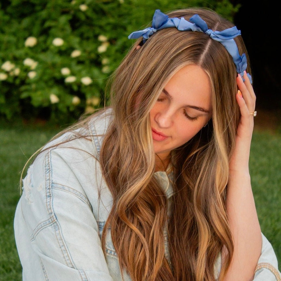This sleek headband is made from soft, silky fabric in a charming blue color. With delicate bow accents, it's the perfect addition to any outfit. This headband is both comfortable and stylish! Give your hair a little something extra with this precious accessory.
