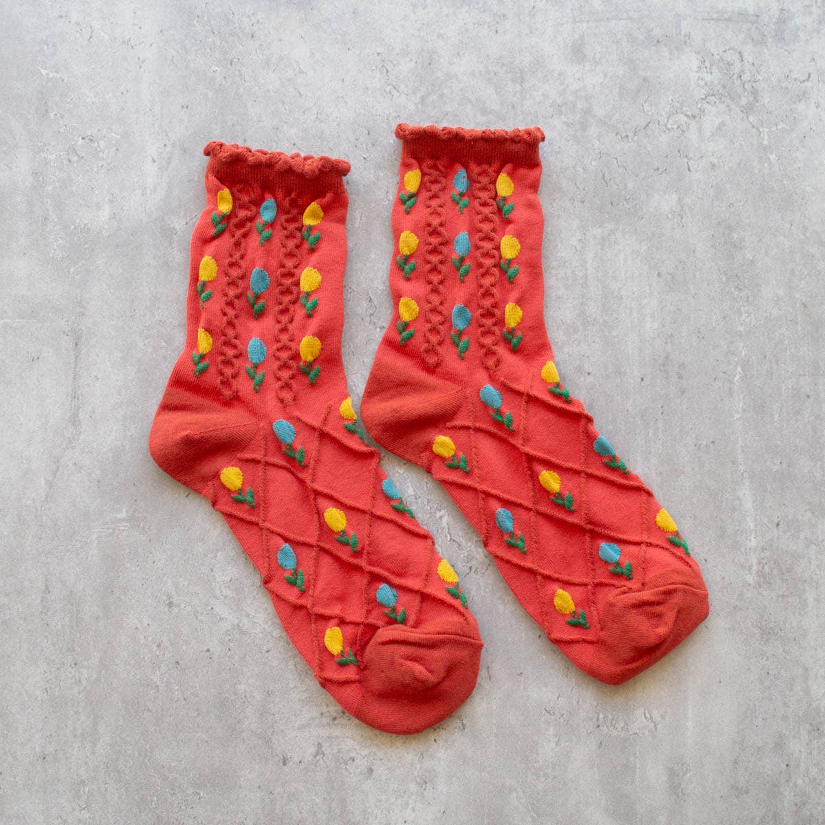 Step into spring with our Tulip Flower Sock in Coral! These dainty floral crew socks feature a vibrant color and playful tulip pattern. Add a touch of whimsy to your wardrobe and keep your feet cozy in style.