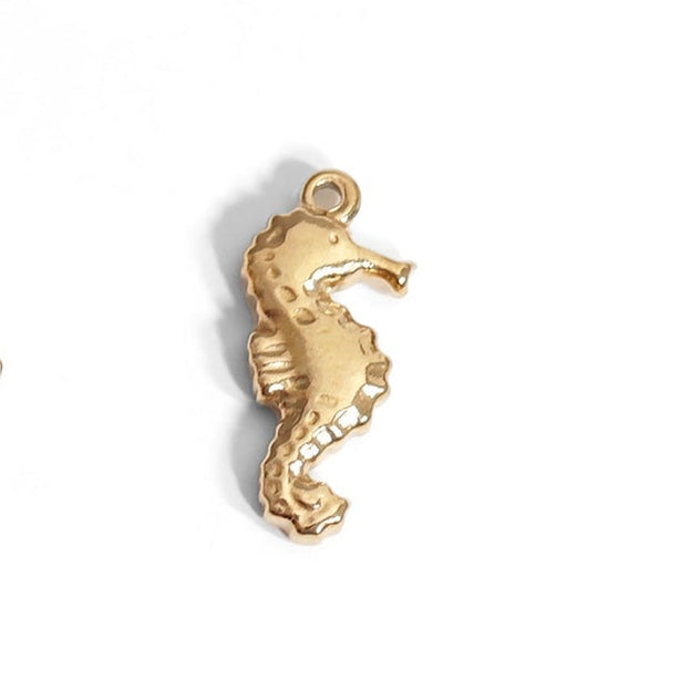 Add a touch of fun to your jewelry collection with our Gold Sea Horse Charm. This nautical-inspired charm features a vibrant gold color that will add a pop of personality to any outfit. Perfect for those who love a playful, beachy vibe!