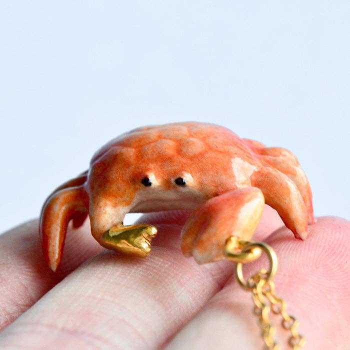 Set sail on a fashion adventure with our limited-edition  Crab 'Golden Grip' Necklace! This handcrafted porcelain pendant features a charming crab complete with a dazzling gold-covered claw, capturing the essence of summer and the allure of the sea. Strung on a delicate chain, this necklace is the quintessential accessory for any nautical or summer-inspired look. Due to the handmade nature of this product, slight variations in color and design may occur, making each piece truly one-of-a-kind.