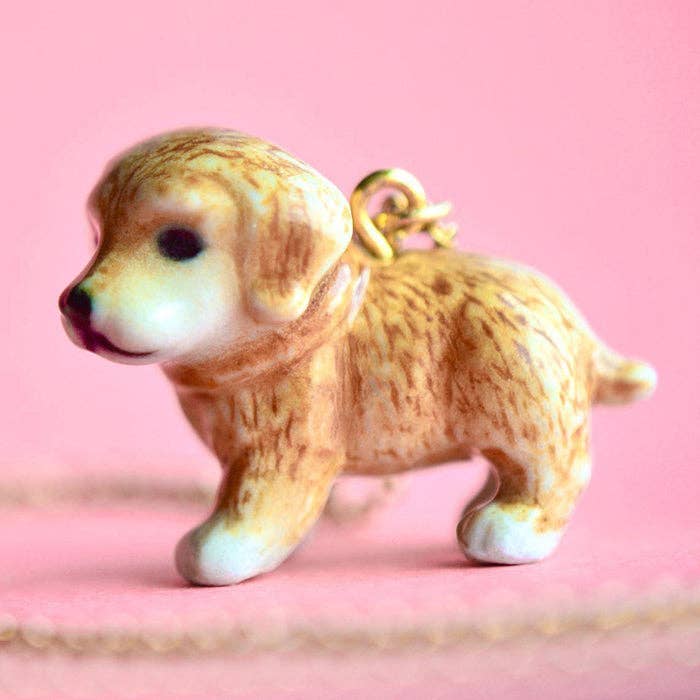 Keep the joy of man's best friend close to your heart with our Golden Retriever Necklace! This porcelain pendant is hand-painted to capture the soft, golden fur of this beloved breed, complete with a shiny gold collar. Strung on a genuine gold chain, it's a heartfelt tribute to your favorite pup. Due to the handmade nature of this product, slight variations in color and design may occur, making each piece truly one-of-a-kind. Perfect for dog lovers and fans of this friendly breed.