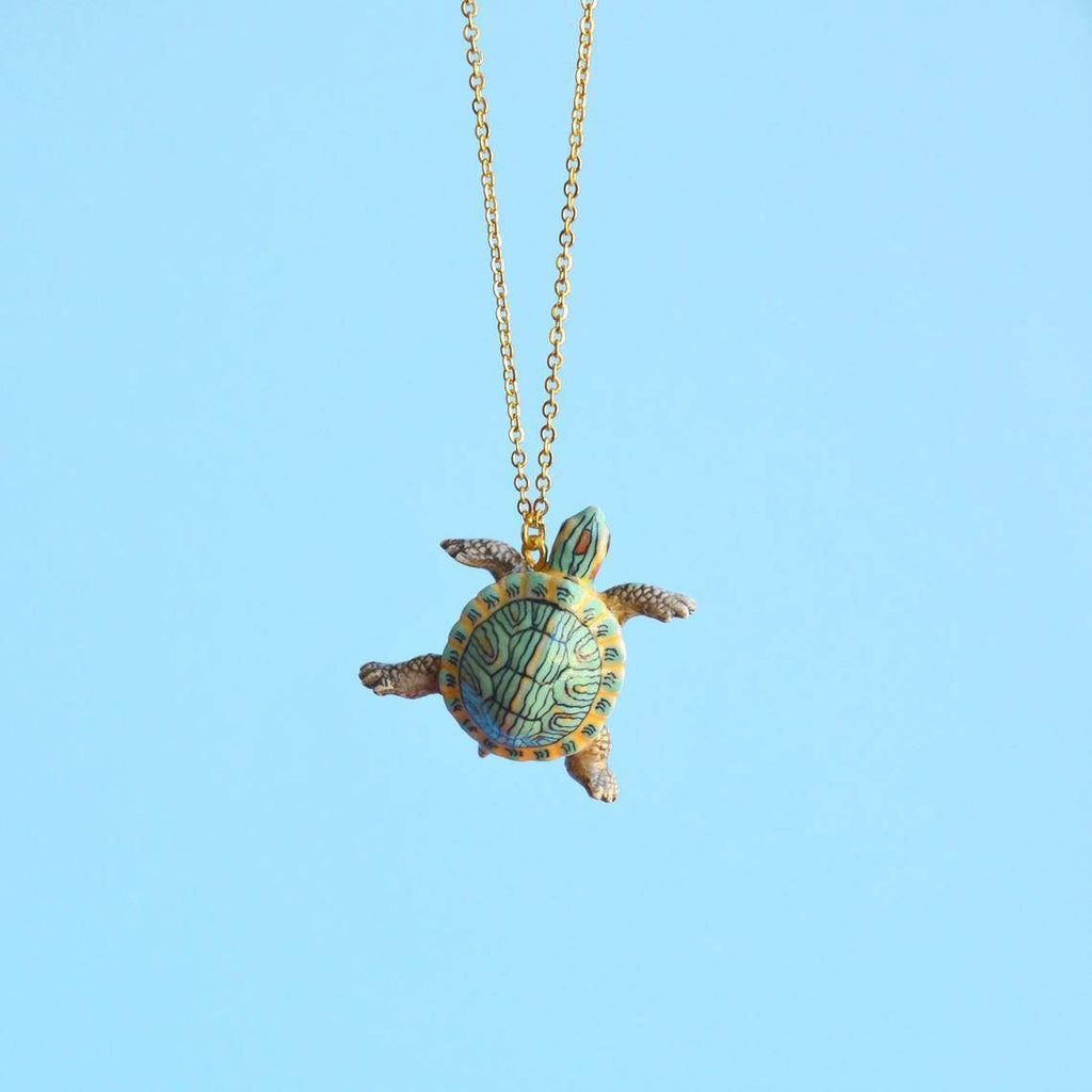 Experience the joy of turtle companionship—no feeding required—with our limited-edition Turtle Necklace! This handcrafted porcelain pendant captures the charm of the red-eared slider, America's most beloved pet turtle, in exquisite detail. Strung on a delicate chain, this necklace is a versatile and endearing addition to any ensemble, from casual daywear to elegant evening attire.
