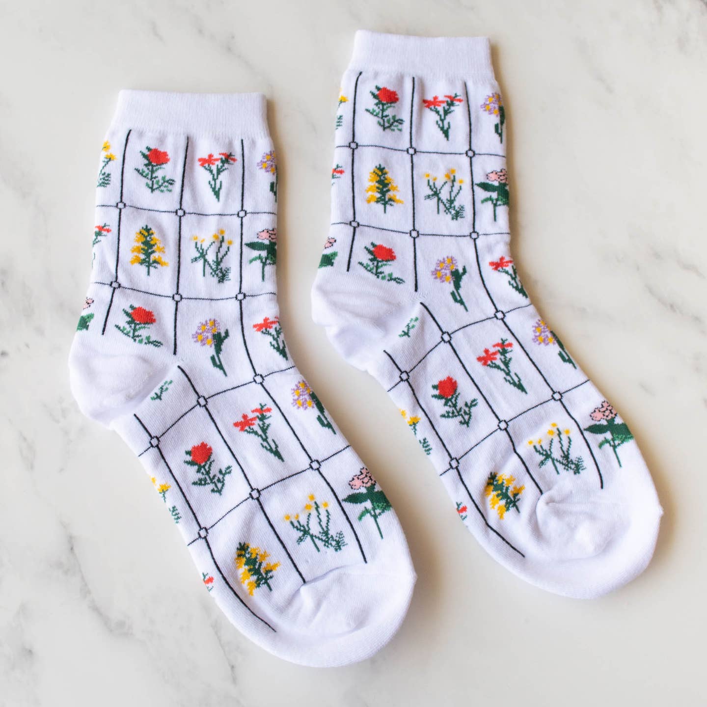 Add a touch of whimsy to your outfit with these playful white floral socks! Featuring a charming botanical pattern, these socks are made to make a statement. Get ready to turn heads and show off your fun side with these quirky socks.