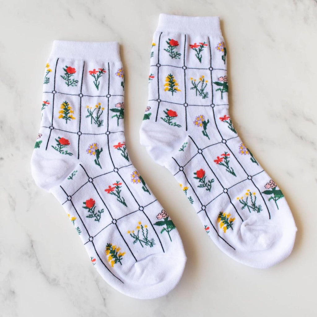 Add a touch of whimsy to your outfit with these playful white floral socks! Featuring a charming botanical pattern, these socks are made to make a statement. Get ready to turn heads and show off your fun side with these quirky socks.