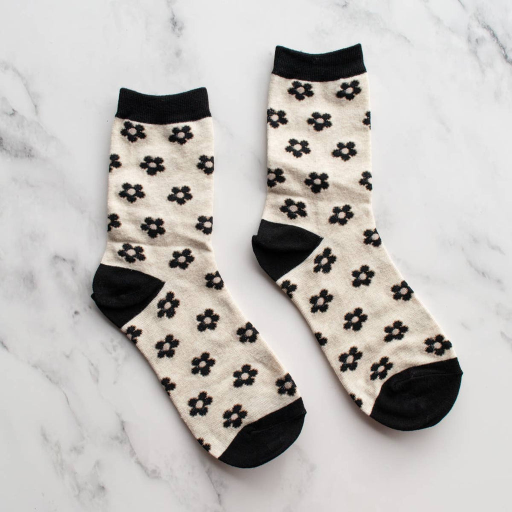 Add a touch of whimsy to your style with our Black & Oatmeal Doodle Flower Crew Socks. The black daisy flower design adds a playful element, while the oatmeal color gives a cozy feel. Stay comfortable and fashionable all day long!
