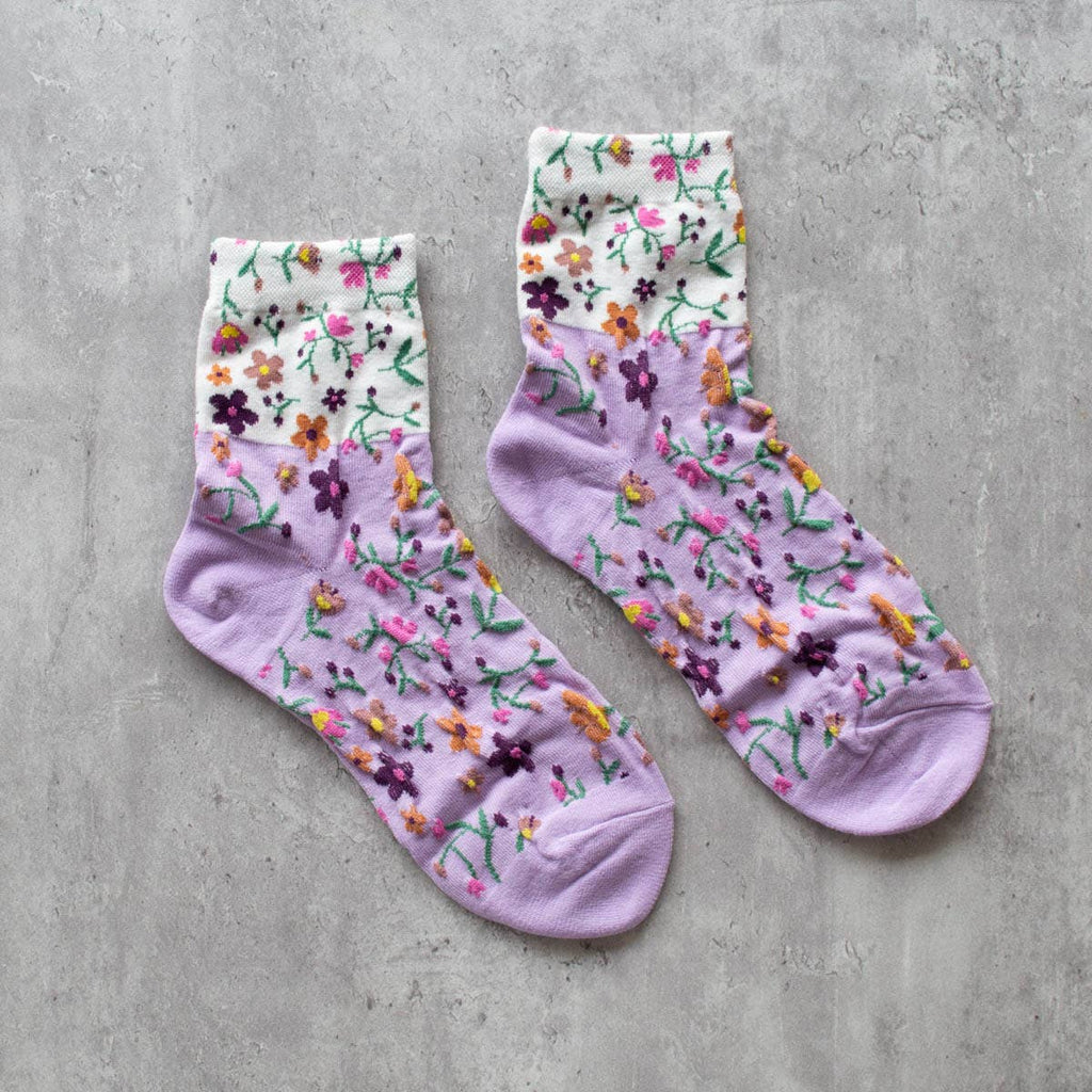 Keep your feet cozy and stylish with our lavender floral 2 toned socks. Featuring a delicate floral design on a soft lavender and white base color, these crew socks are the perfect addition to your wardrobe. Stay comfortable and fashionable all day long!