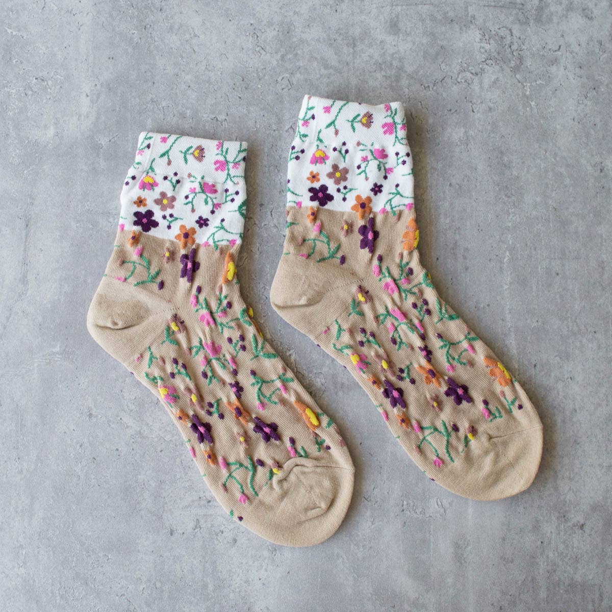 Keep your feet cozy and stylish with our taupe floral 2 toned socks. Featuring a delicate floral design on a soft taupe and white base color, these crew socks are the perfect addition to your wardrobe. Stay comfortable and fashionable all day long!
