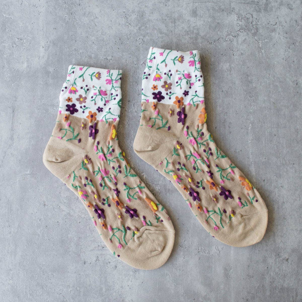 Keep your feet cozy and stylish with our taupe floral 2 toned socks. Featuring a delicate floral design on a soft taupe and white base color, these crew socks are the perfect addition to your wardrobe. Stay comfortable and fashionable all day long!