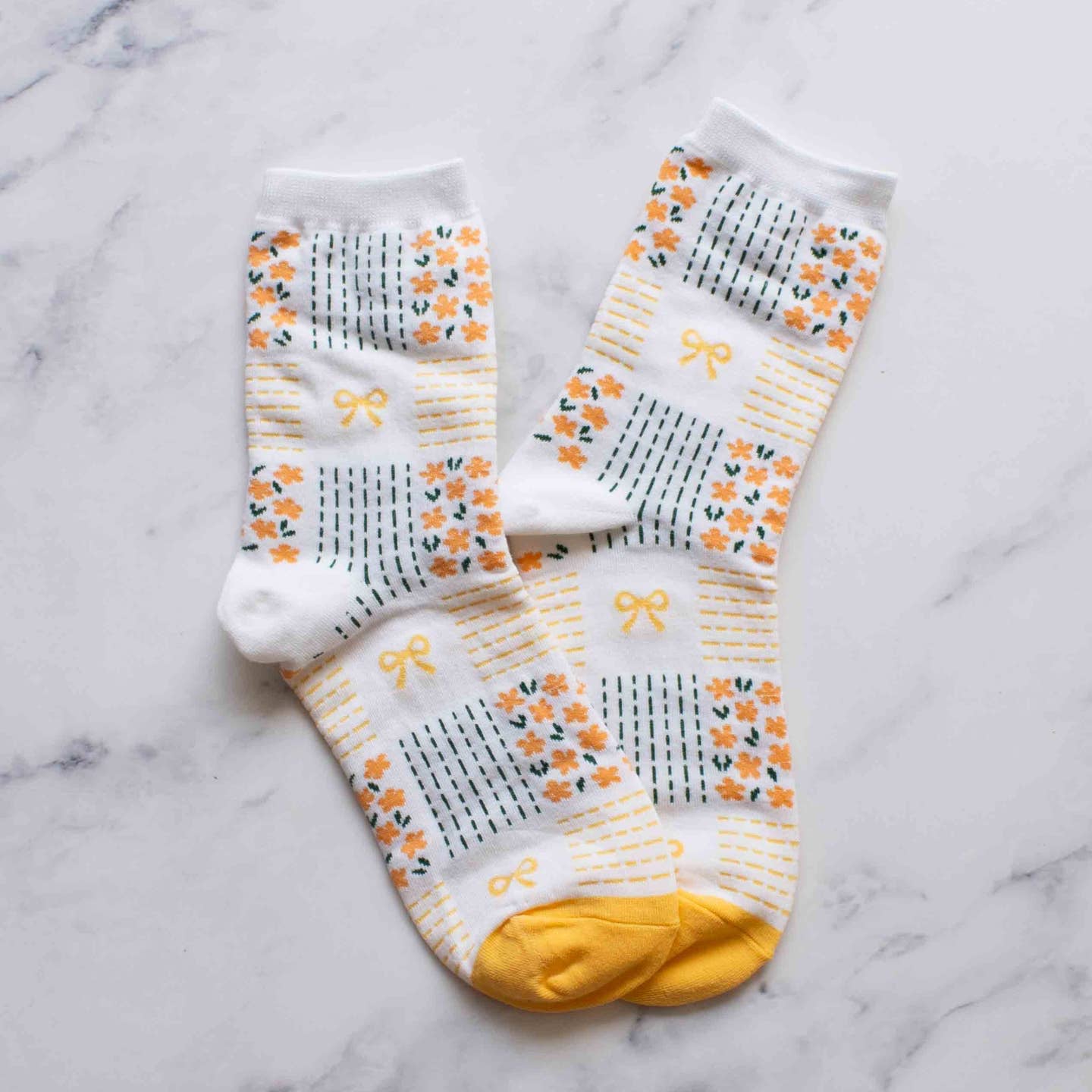 Slip into style with our Yellow Remi Ribbon & Floral Socks. The soft yellow floral pattern and delicate tiny bows add a touch of elegance to these crew socks. Step up your sock game and treat your feet while showing off your fashion sense.