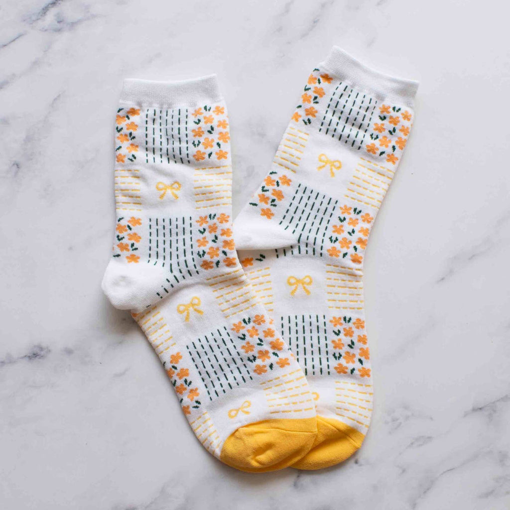 Slip into style with our Yellow Remi Ribbon & Floral Socks. The soft yellow floral pattern and delicate tiny bows add a touch of elegance to these crew socks. Step up your sock game and treat your feet while showing off your fashion sense.