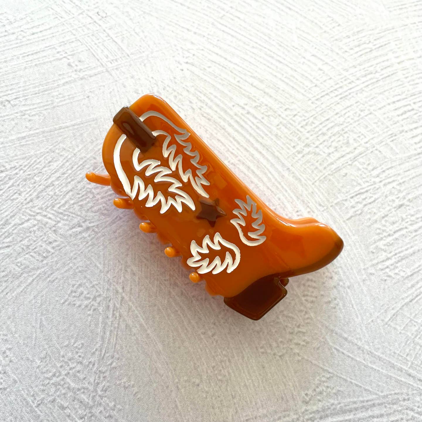Western Boot Hair Claw Clip, the perfect accessory for any Western-inspired outfit. Made with sustainable materials, this clip showcases an intricate boot design and features a secure, easy-to-use grip. Upgrade your hair game with this eco-friendly and stylish clip.