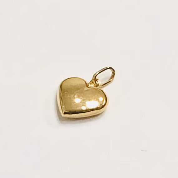 Add a touch of sweetness to your bracelet or necklace with our Gold Puffy Heart Charm. Its dainty and puffy heart design will add a delicate and charming touch to any accessory. With its beautiful gold color, it's the perfect addition to any jewelry collection.