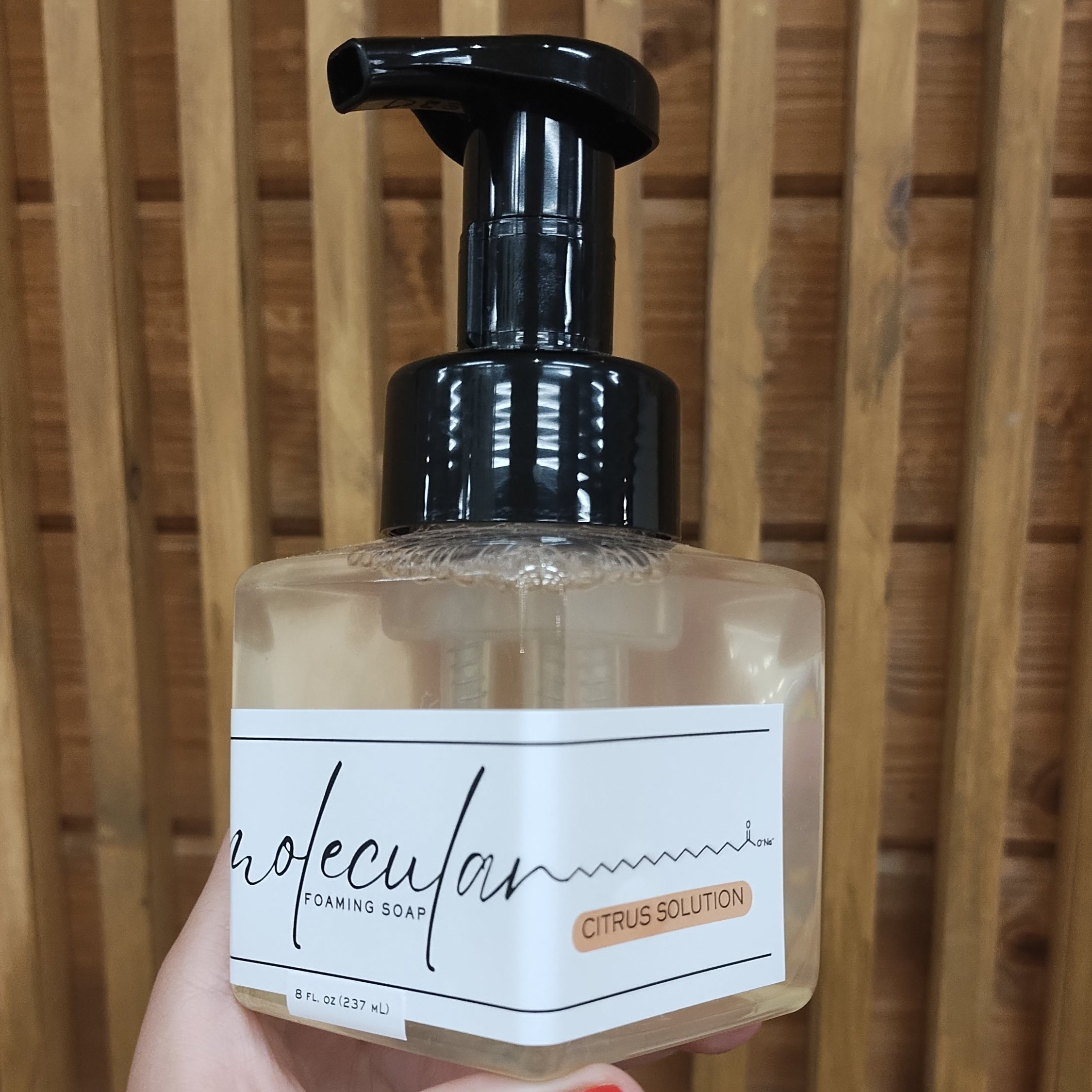 Square plastic bottle with black pump and white minimalistic label. 