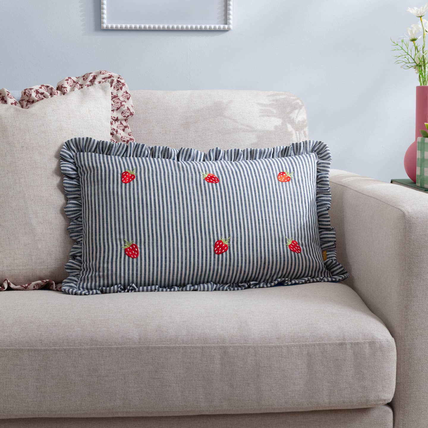 Add a touch of elegance and whimsy to your home with the Les Fruites Striped Ruffle Cushion. The delicate ruffle trim and classic pinstripe design evoke timeless charm, while the playful fruity and floral embroidery brings a fresh, contemporary twist. Crafted for those who appreciate fine details, this cushion effortlessly combines relaxed sophistication with personality to elevate any interior. Its versatile design is perfect for creating a welcoming, stylish space that leaves a lasting impression.