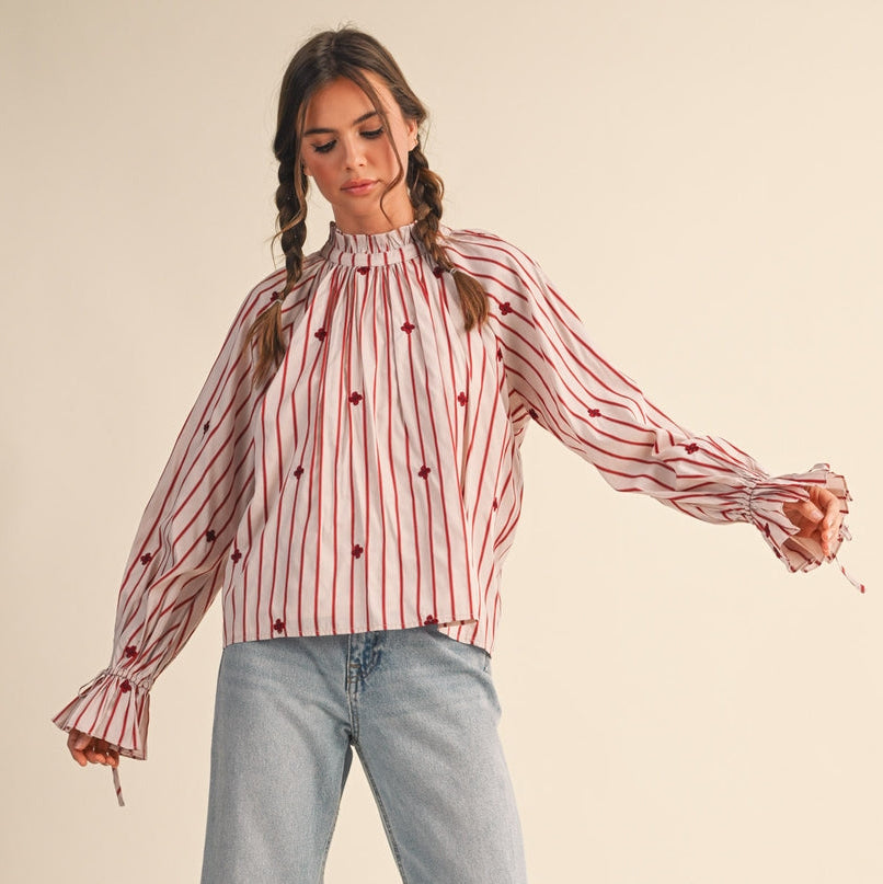 This women's long sleeve blouse features elegant wine-colored pinstripes and delicate tiny embroidered flowers, adding a subtle touch of charm. The ruffle neck detail enhances its feminine appeal, making it a versatile piece for both work and casual outings. Comfortable and stylish, it’s designed to support your confidence and grace throughout the day.