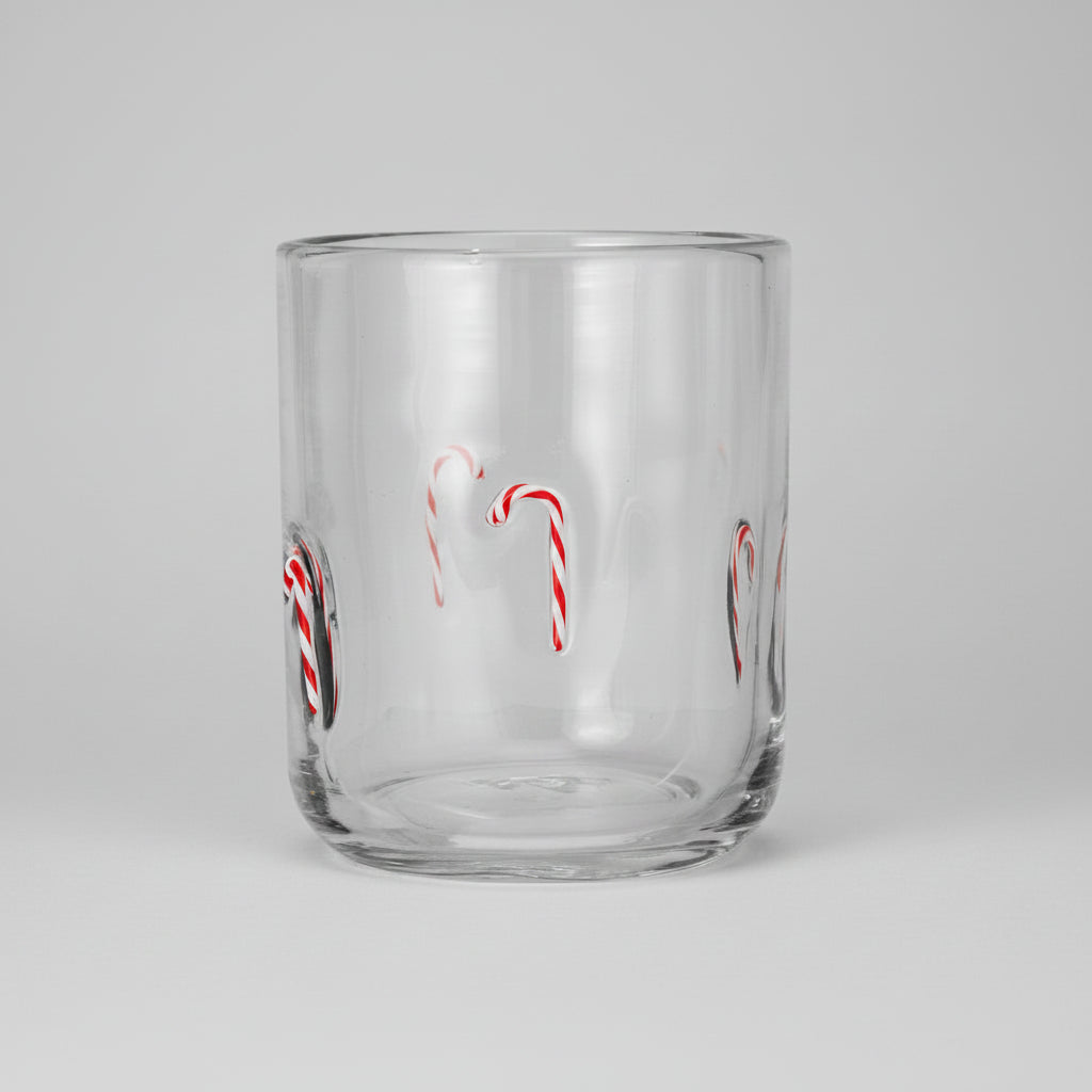 A clear glass tumbler with red and white candy cane illustrations on the sides, shown against a plain white background.