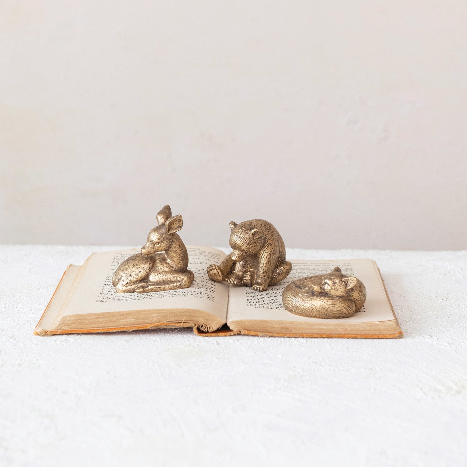 Three bronze animals figurines on an open book with a white background