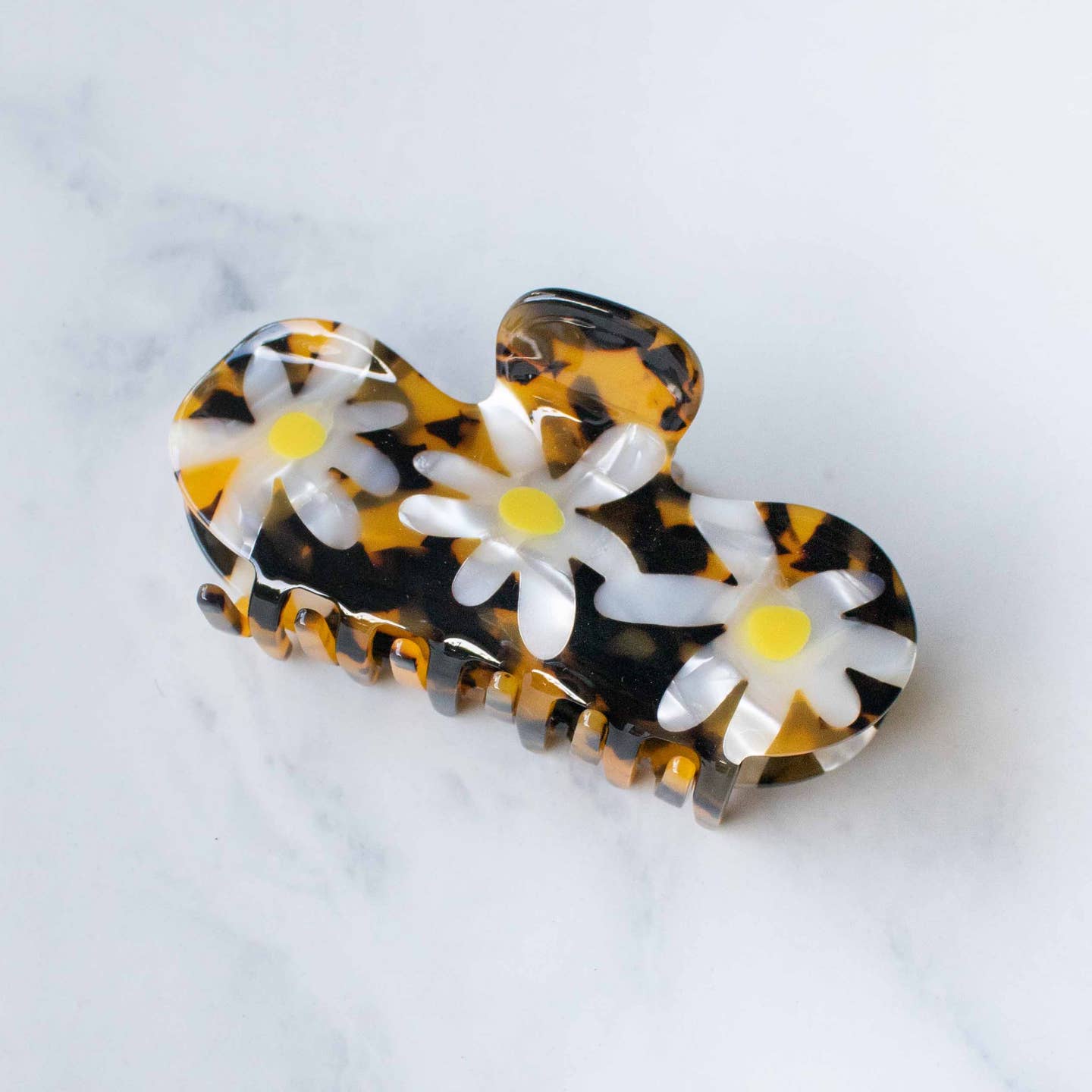 Add a cheerful touch to your hairstyle with this Daisy Curved Hair Claw Clip in amber tortoise. Featuring three detailed daisies and a smooth curved top, it holds your hair gently yet securely throughout the day. Perfect for adding a burst of color while keeping your hair comfortably in place.

Material: Cellulose Acetate