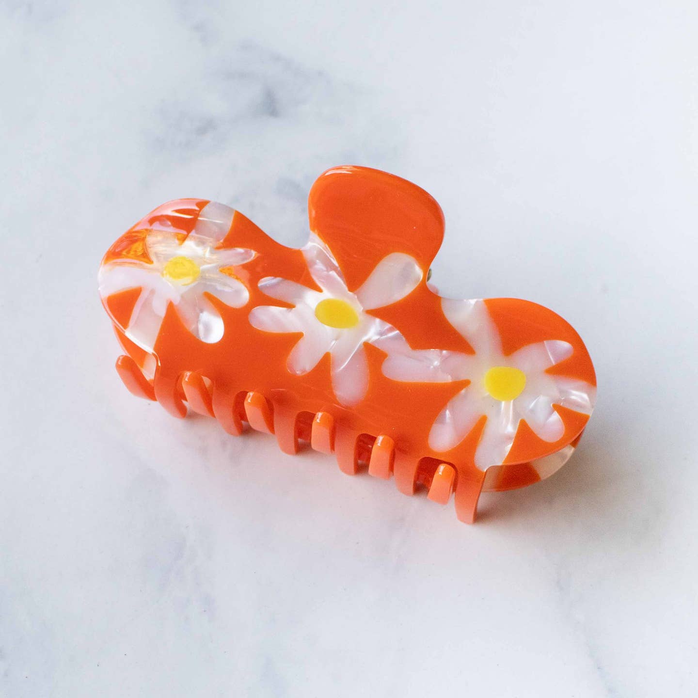 Add a cheerful touch to your hairstyle with this Daisy Curved Hair Claw Clip in vibrant orange. Featuring three detailed daisies and a smooth curved top, it holds your hair gently yet securely throughout the day. Perfect for adding a burst of color while keeping your hair comfortably in place.

Material: Cellulose Acetate
