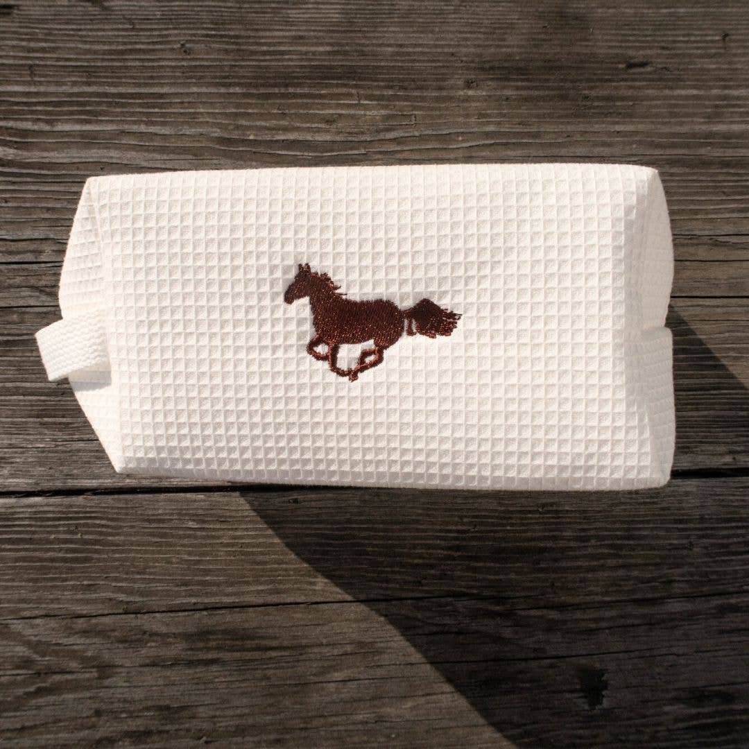 The perfect mix of cozy and cowboy, made from super soft 100% cotton waffle fabric that feels light but still durable. And that embroidered horse? (We call him Smokey, named after my Uncles horse that loves to have his picture taken.) So cute and just the right touch of Western charm!

At about 7.9” x 3.9” x 4.7”, it’s the perfect size to toss in your tote or carry-on—roomy enough for all your makeup, skincare, or whatever little essentials you need on the go.