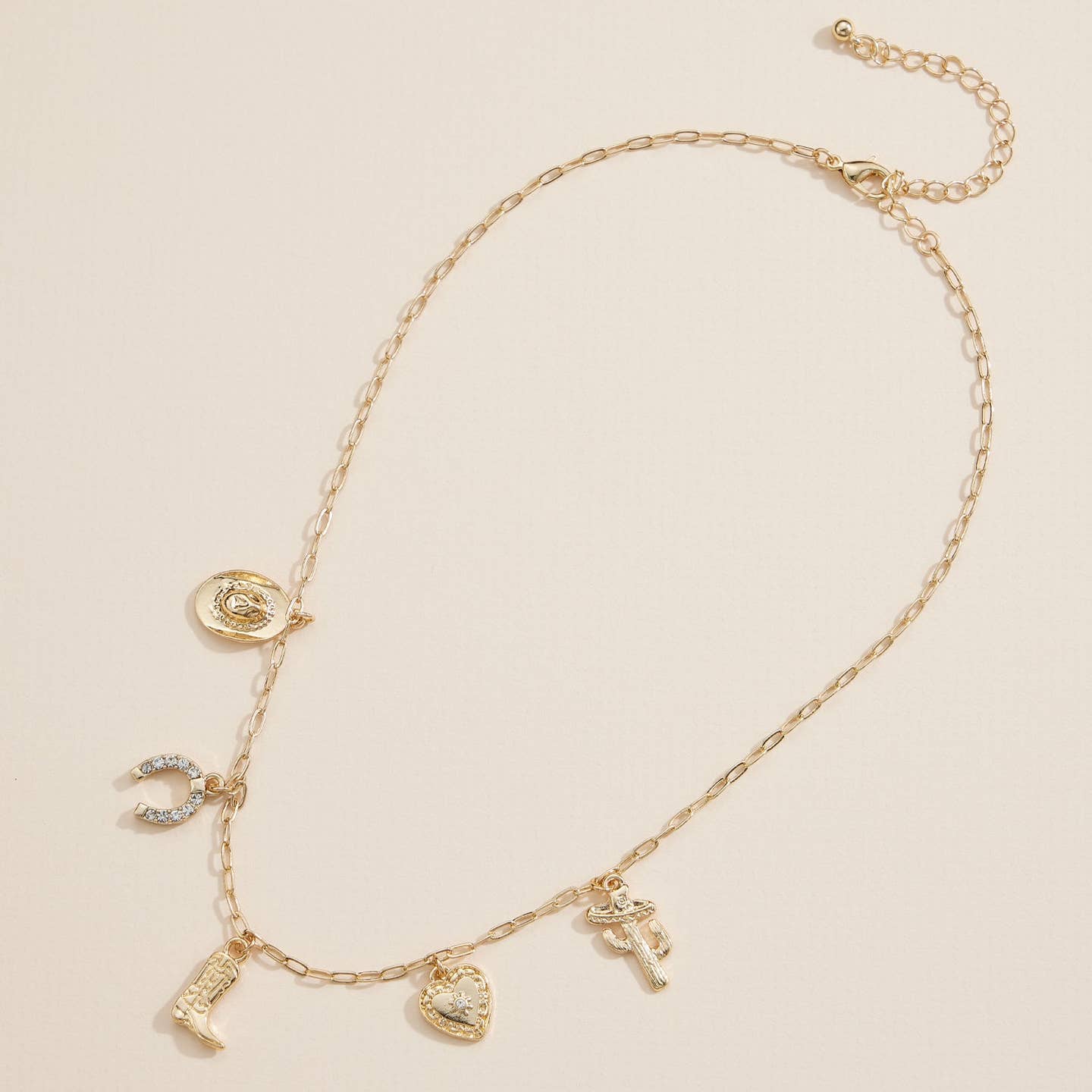 Embrace a touch of the Wild West with this western-inspired charm necklace, available in gold-tone and silver-tone finishes. This eye-catching piece features unique western-themed charms including a horseshoe, cowboy boot, hat, cactus, and heart pendant with crystal accents. The lightweight chain comes with an adjustable length for the perfect fit, making it a versatile statement accessory. Perfect for country lovers, rodeo fans, or anyone looking to add a fun, rustic twist to their jewelry collection. 18”.