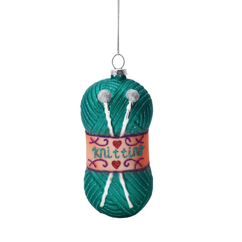 Decorative ornament shaped like a skein of yarn with knitting needles, on a white background.