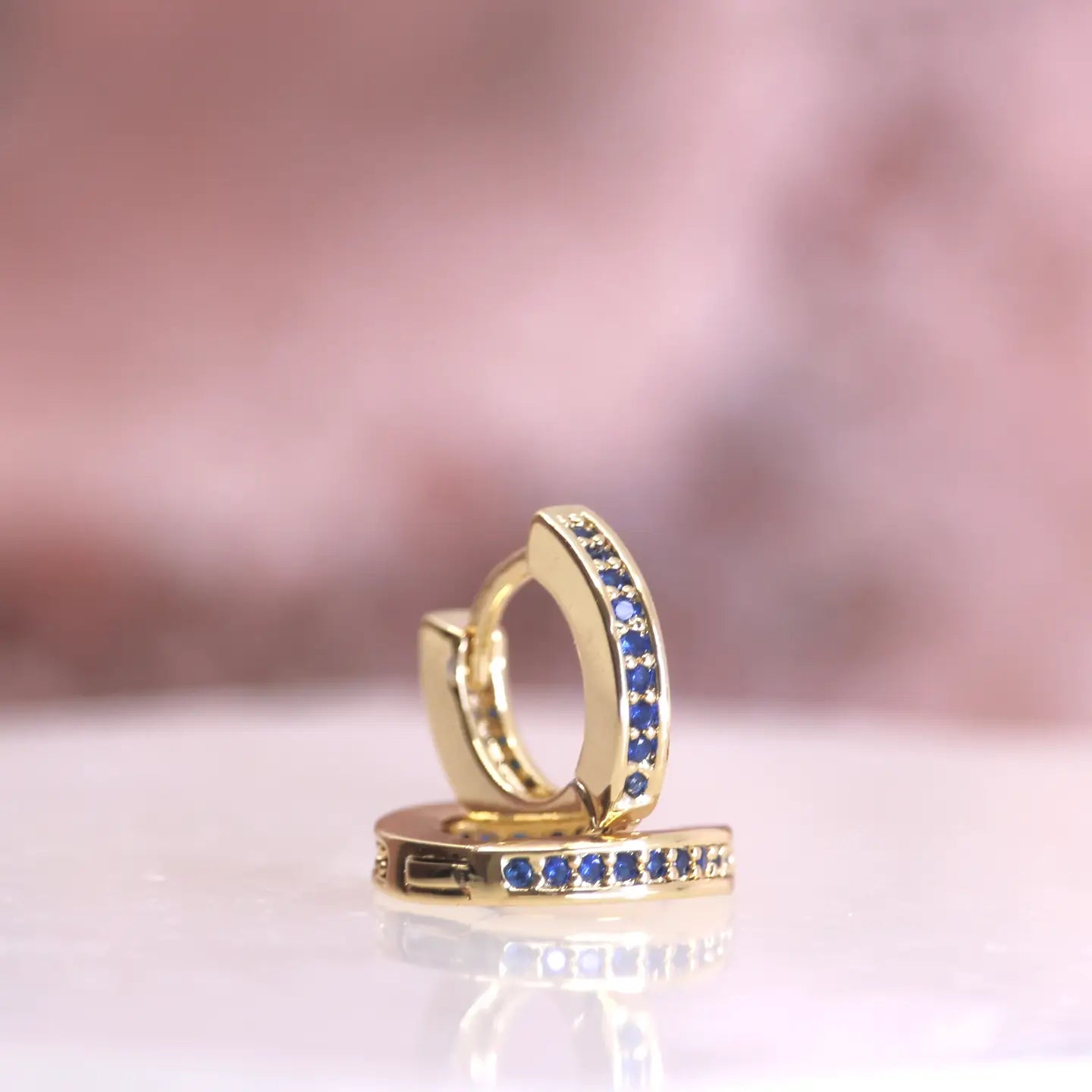 These hoops are named after the star that resides in the Corona Borealis Constellation. This star has a blue and white appearance. It's latin sources name, Alphecca, is associated with inspiration and creativity. Glow with blue czs in these shinning hoops.