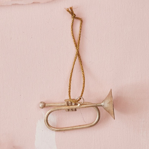 Small brass trumpet ornament on a pink background