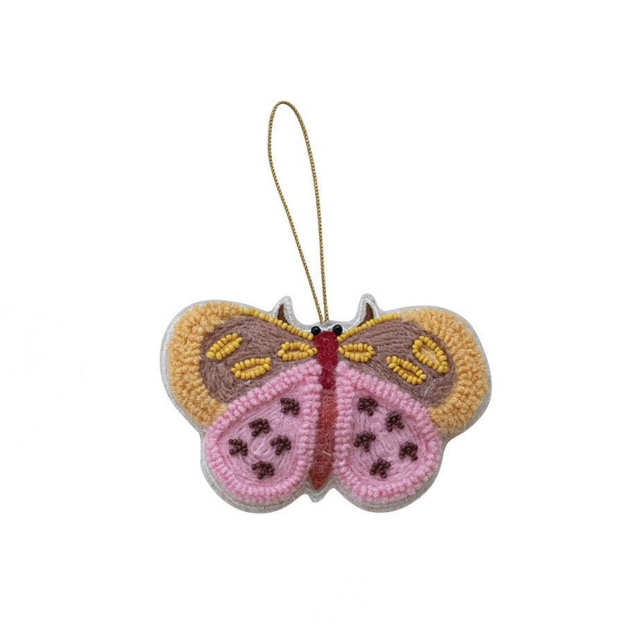Crocheted butterfly ornament with pink body and yellow wings on a white background