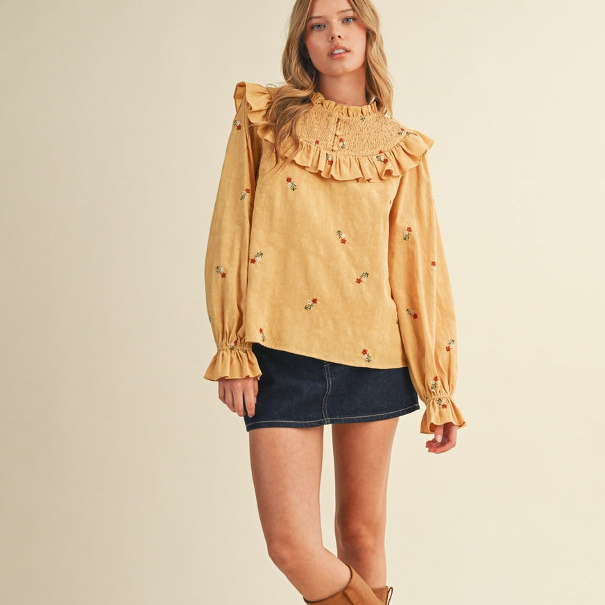 This mustard yellow blouse features delicate tiny embroidered flowers and a comfortable smocked yoke for a flattering fit. The long sleeves add a touch of elegance, making it perfect for both casual and dressier occasions. Its soft fabric and thoughtful design ensure you feel confident and comfortable all day long.

Details:

Ruffled smocked yoke embroidered blouse
Ruffled neckline with buttons
Smocked front yoke with ruffle trim
All over floral embroidery
Long puff sleeves with ruffled cuffs
Lined