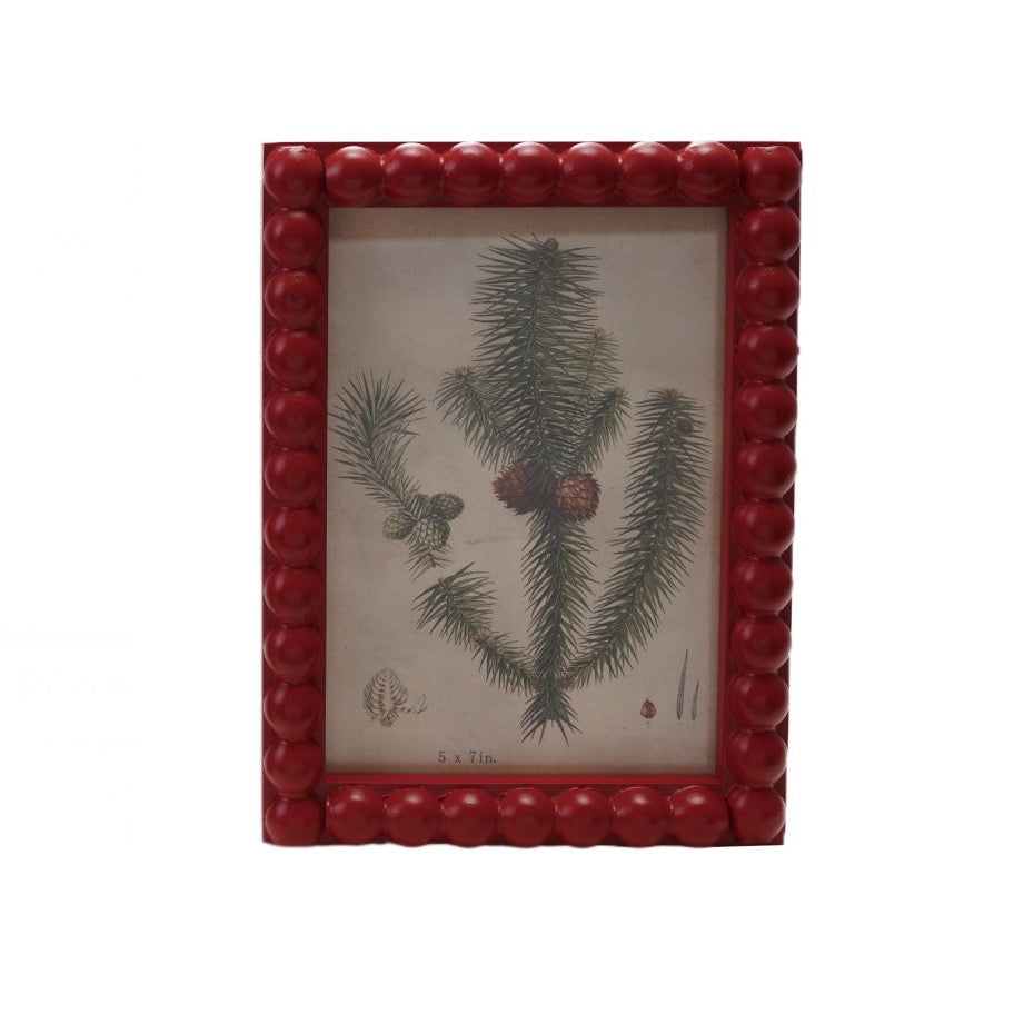 This Wood Hobnail Red Photo Frame beautifully showcases your 5x7 photos with its classic red finish and charming hobnail texture. Featuring a serene winter greens print inside, it adds warmth and seasonal elegance to any space while protecting your cherished memories. Perfect for displaying your favorite moments with a touch of timeless style.

Details:

Holds 5" x 7" Photo
Dimensions: 5.9” x 8”