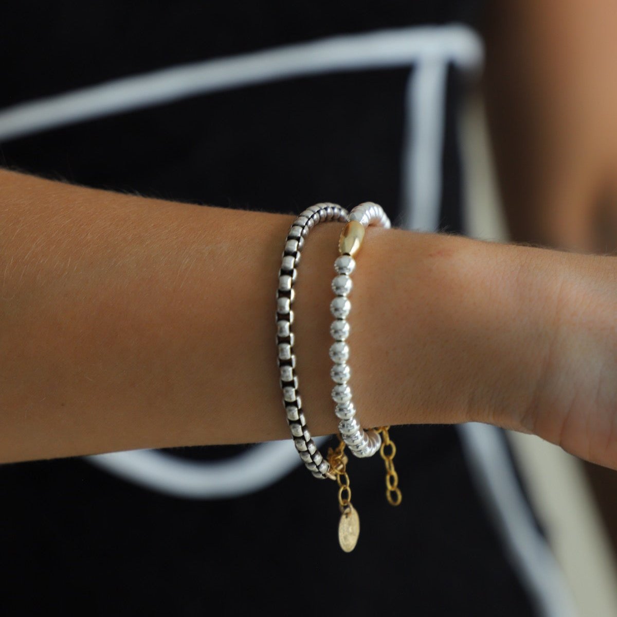 Introducing the Nova Chain Bracelet - a stunning, two tone accessory featuring a round silver box chain with a gold lobster clasp and end chain with a coin drop. The perfect blend of elegance and edge, this bracelet will elevate any outfit with its sleek, modern design.