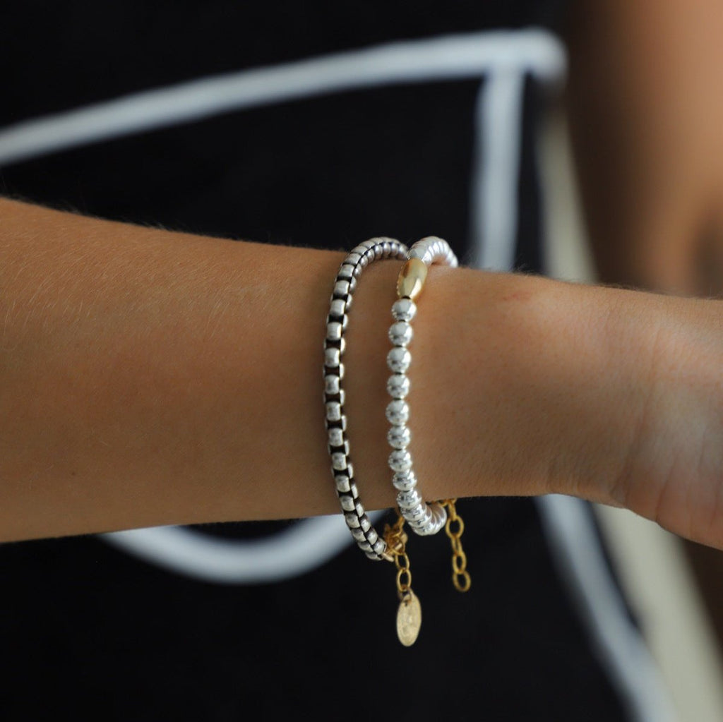 Introducing the Nova Chain Bracelet - a stunning, two tone accessory featuring a round silver box chain with a gold lobster clasp and end chain with a coin drop. The perfect blend of elegance and edge, this bracelet will elevate any outfit with its sleek, modern design.
