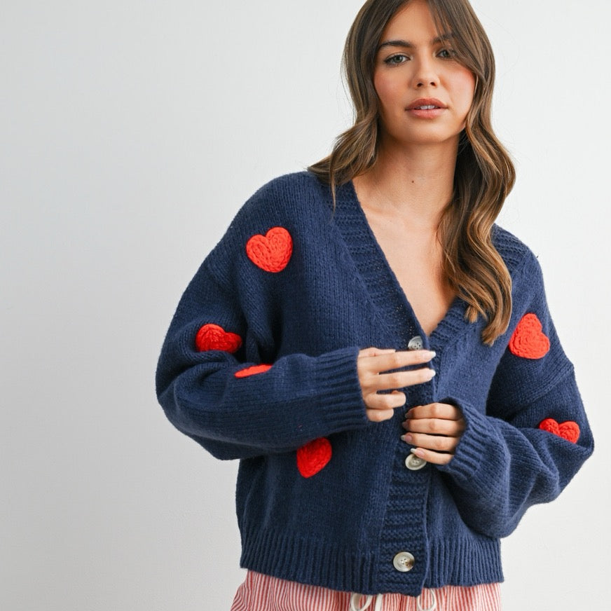 Add a touch of charm to your look with this Heart Pattern V-Neck Cropped Cardigan Top. Featuring a soft knit fabric, cute heart prints, and a flattering cropped fit, it's perfect for layering or wearing on its own. The button-down front and V-neckline offer a classic touch, making it a sweet and stylish choice for any casual outfit.
