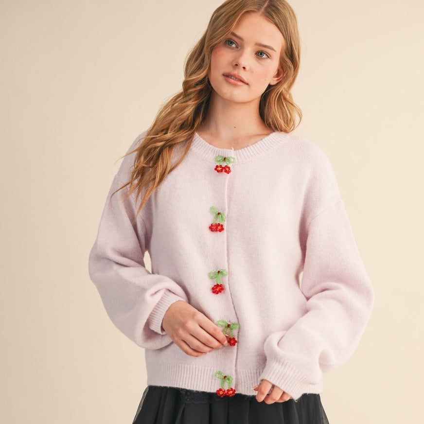 Elevate your everyday style with this charming cardigan featuring soft pink tones and delicate beaded bow and floral button details. Each button is a miniature work of art, adding a whimsical touch to your wardrobe. Perfect for layering over dresses or pairing with your favorite jeans, this piece brings a feminine, thoughtful elegance to any outfit. The supportive structure and quality construction ensure you'll reach for it again and again, making it a versatile staple.