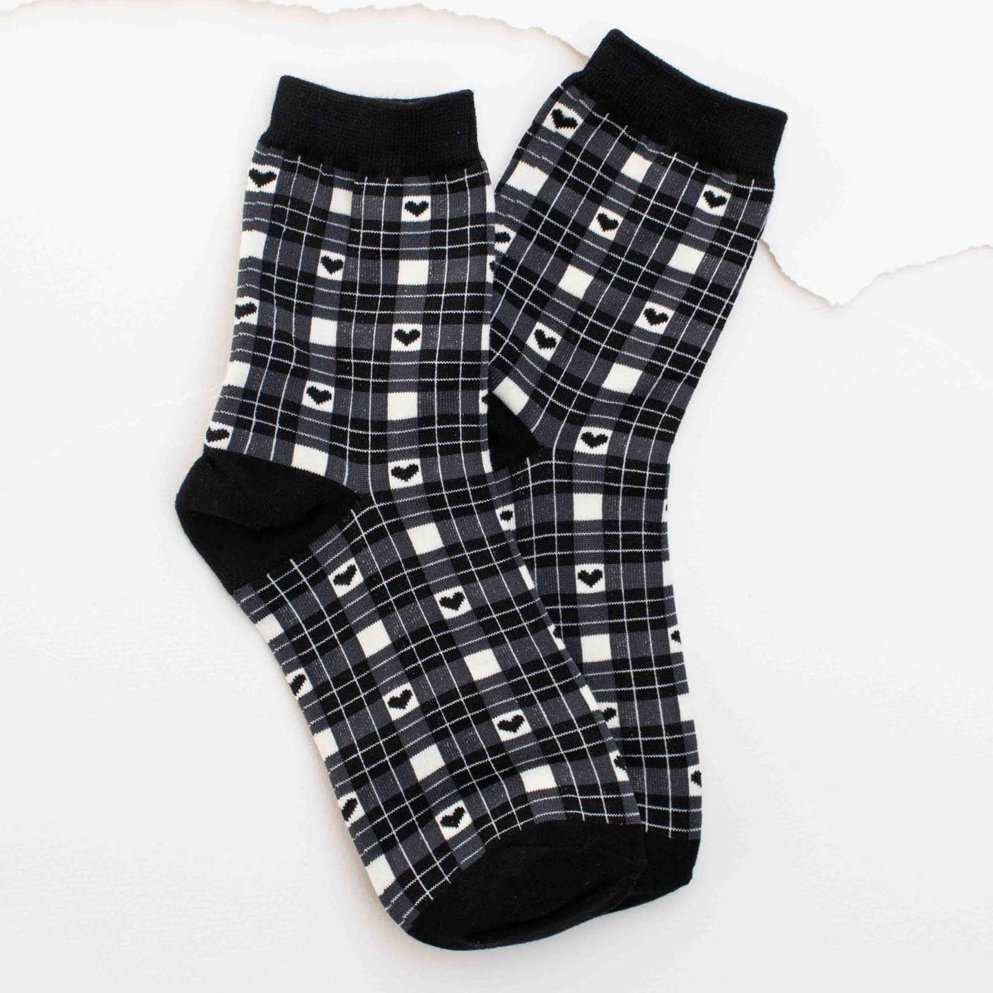 Wrap your feet in cozy comfort with these charming black plaid crew socks. Featuring a classic plaid pattern adorned with sweet hearts throughout, they bring a touch of warmth and personality to your everyday style. Perfect for layering in boots or pairing with sneakers, these socks offer the softness and support your feet deserve. A delightful way to add a little love to your sock drawer.