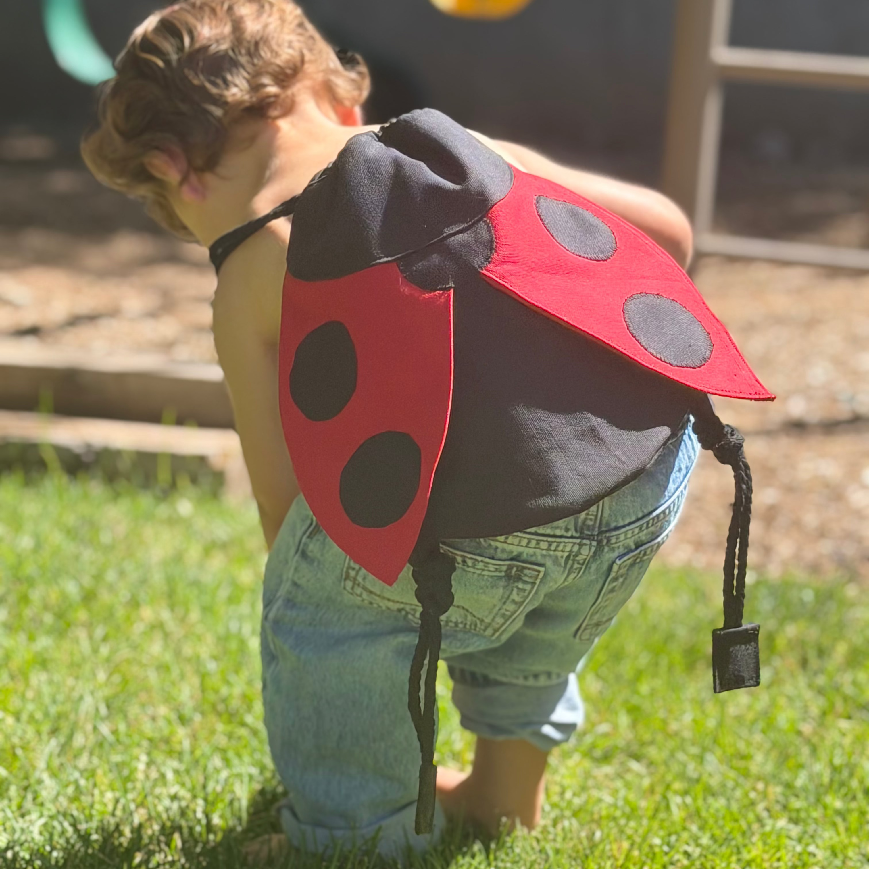 Small children's drawstring backpack with red ladybug wing flaps. 