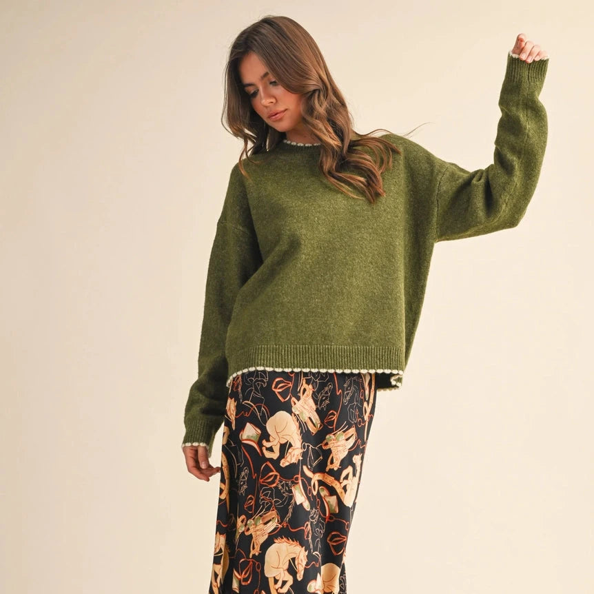 Wrap yourself in effortless comfort with this slouchy olive green sweater. The soft heathered knit drapes beautifully with relaxed drop shoulders, while delicate scalloped edges in contrast knit add a charming, refined touch at the neckline, cuffs, and hem. Ribbed details keep everything in place without sacrificing that cozy, lived-in feel. Perfect for layering on cool days or wearing solo for understated style.
