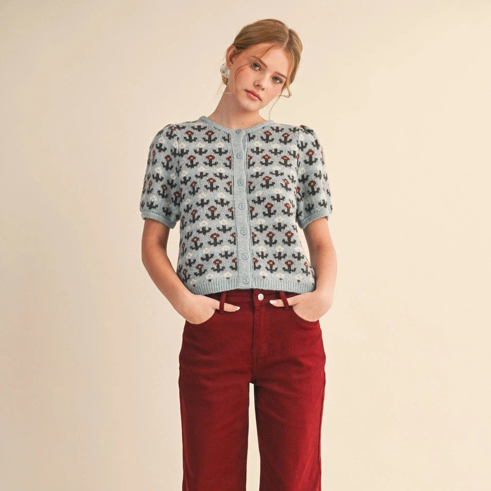 Embrace effortless style with this charming short sleeve knit sweater in cool blue and brown tones. Delicate flowers dance across the fabric, adding a touch of natural beauty to your everyday wardrobe. The soft, breathable knit construction keeps you comfortable whether you're layering for cooler days or wearing it solo when temperatures rise. Perfect for transitional seasons, this versatile piece pairs beautifully with jeans, skirts, or trousers for a look that feels both polished and approachable.