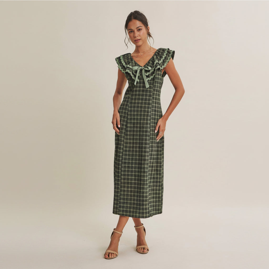 A warm, vintage-inspired piece that instantly brings depth to fall assortments. This plaid midi dress blends nostalgic charm with a clean, flattering silhouette. The ruffled V-neckline is framed with soft ric rac trim, adding texture and a subtle handcrafted feel, while the center bow detail creates a feminine focal point. Designed with a slim, body-skimming fit, this style offers a more refined, tailored look compared to flowy silhouettes, making it a strong option for elevated everyday dressing.